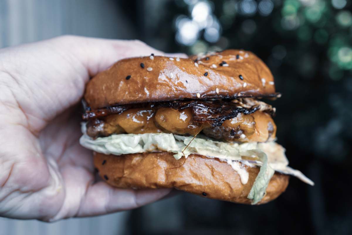 plenty west end person holding burger with meat west end